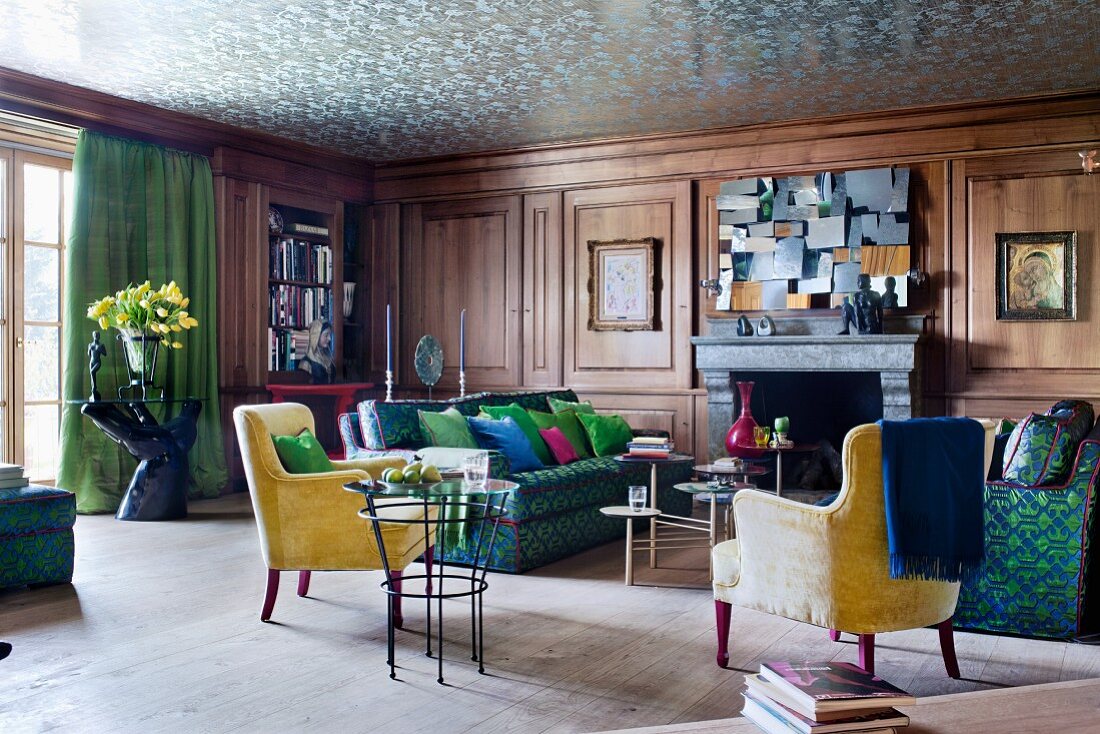 Walnut-panelled salon in blue and green combined with yellow 50s armchairs; silver reflective wallpaper on ceiling creates an illusion of height