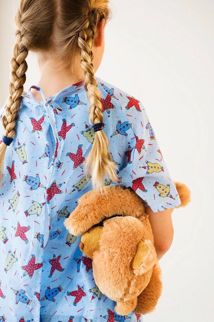 Girl in nightshirt carrying teddy bear