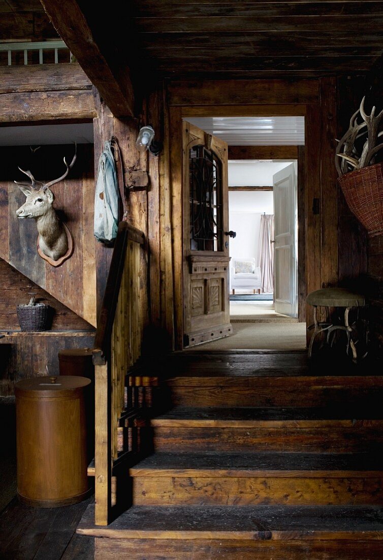 Former barn used as foyer - hunting trophies on wooden wall next to wooden steps leading to open door