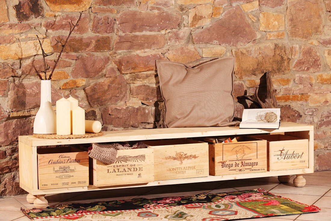 DIY sideboard with wine crates used as storage boxes against stone wall