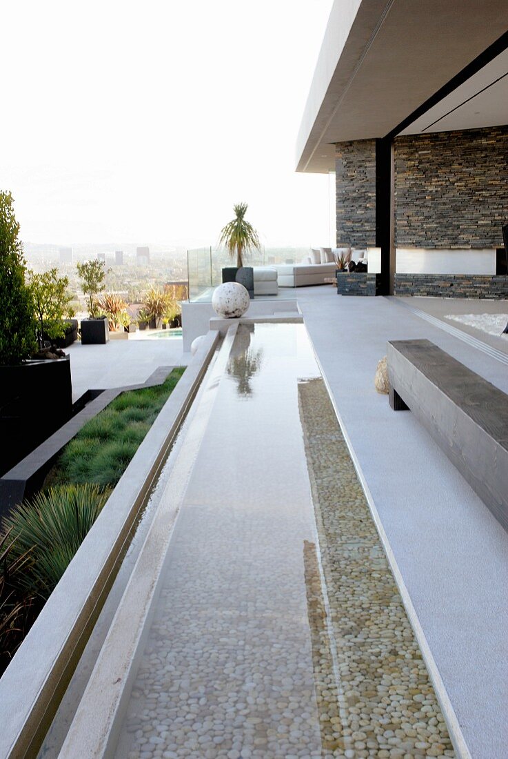 Long, narrow pool adjoining terrace of contemporary house with panoramic view of city