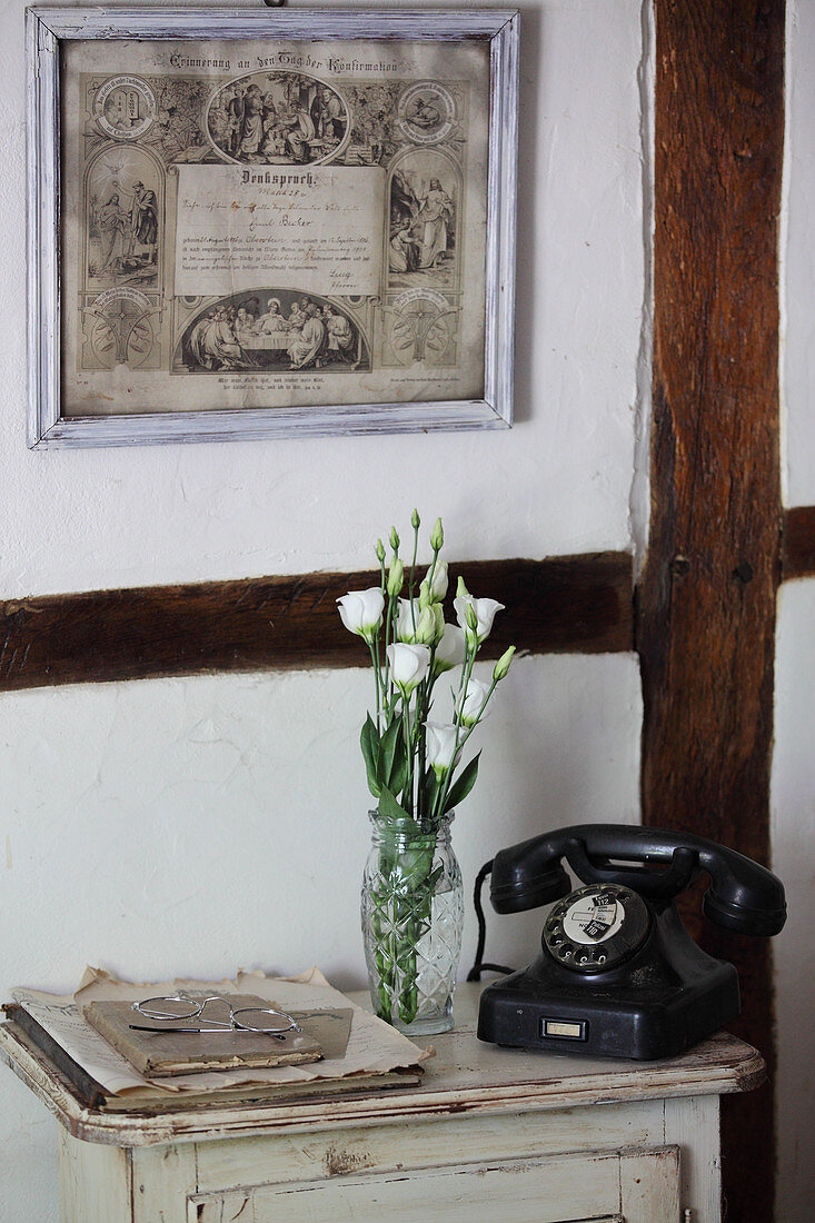 Altes Telefon und Blumen auf einem Tischchen vor Fachwerkwand