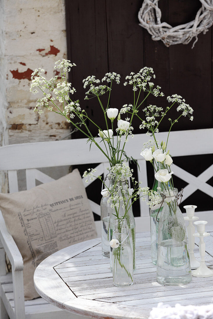 Wiesenblumen und Japanrosen in alten Bügelflaschen auf dem Tisch