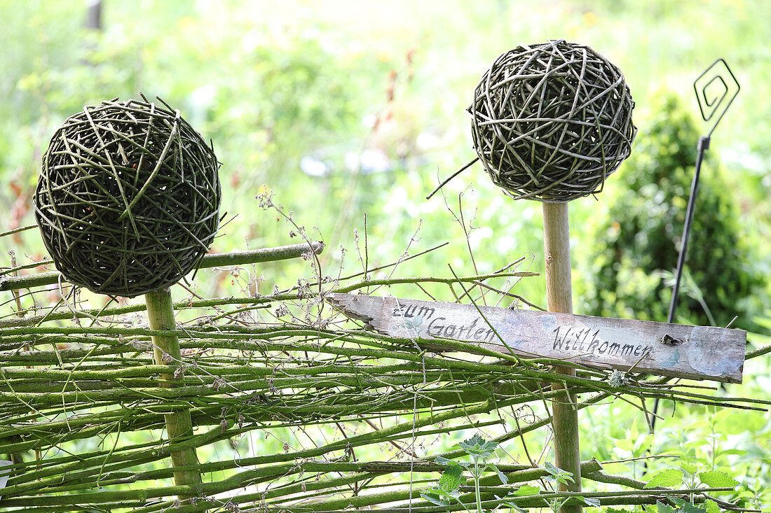 Garden sign on DIY fence with wicker balls on stakes