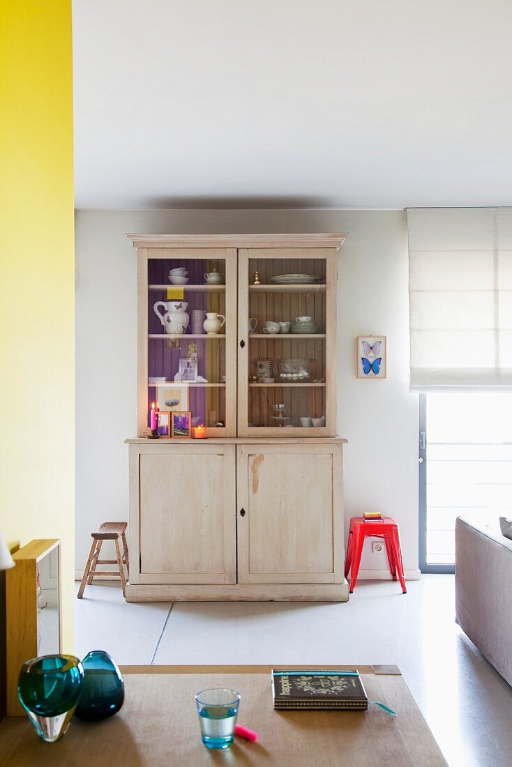 Vitrinen Küchenschrank im Vintagelook mit Geschirr in offener Appartementküche