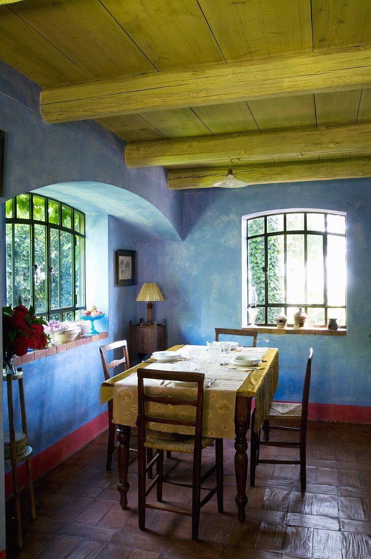Rustikaler Essplatz in mediterranem Landhaus mit blau marmoriertem Wandanstrich zu historischen Sprossenfenstern