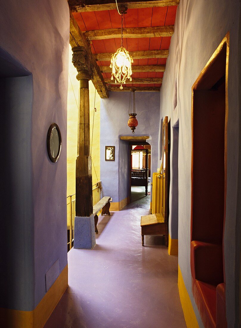 Gangflucht in Lavendelblau mit gelben Akzenten und venezianisch-rot gestrichener Holzdecke als eigenwillige Farbkomposition in historischem Landhaus