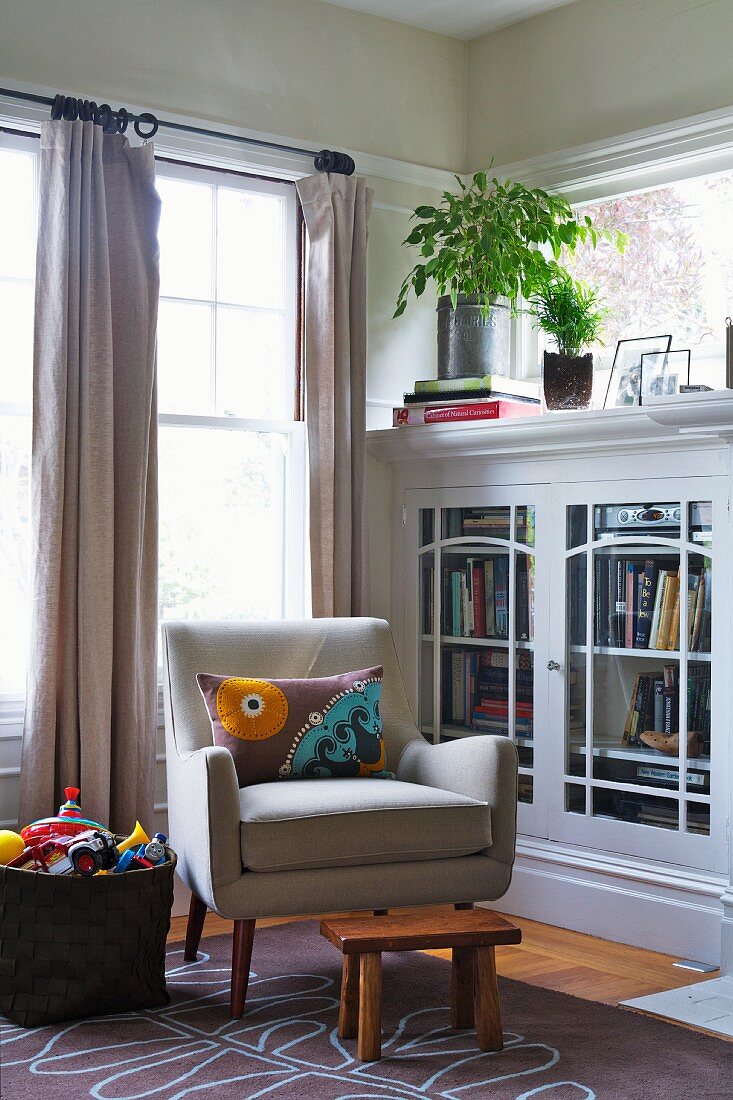 Armchair next to half-height bookcase in corner of living room