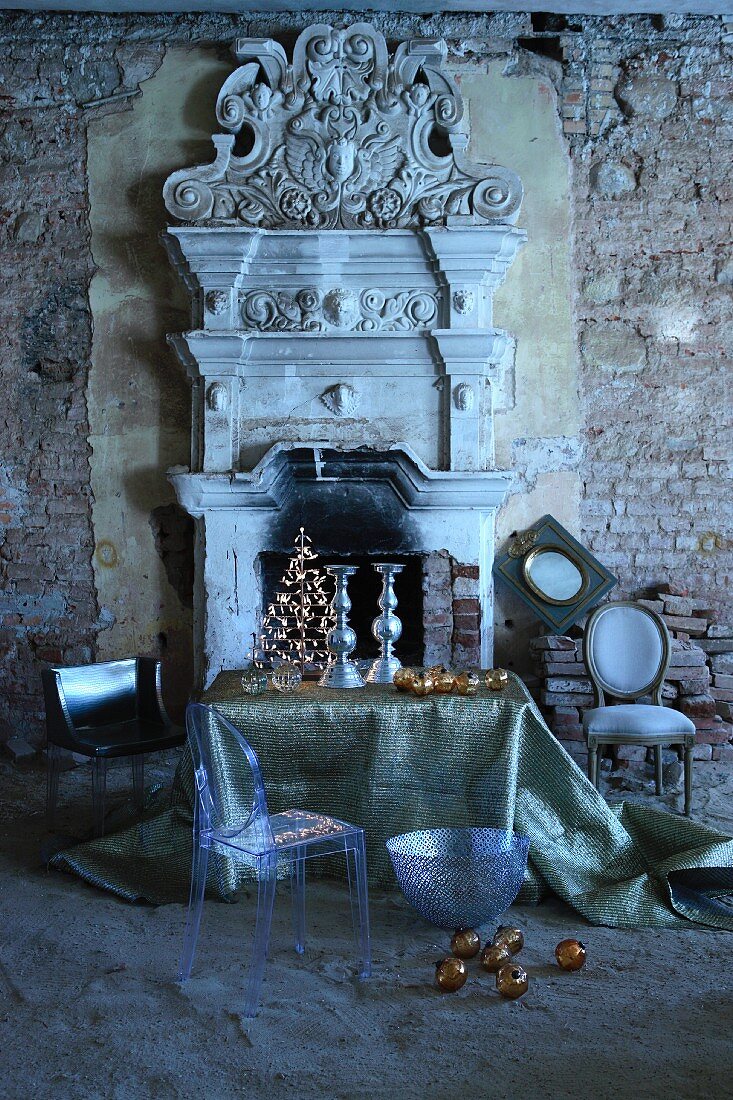 Ghost-Stuhl und Tisch mit Weihnachtsdekoration vor offener Kamin mit griechisch antiken Architekturelementen in ruinenhaftem Ambiente