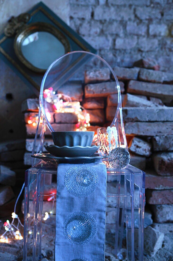 Runner and cafe au lait bowl on Ghost chair in front of rustic stone wall with string of fairy lights