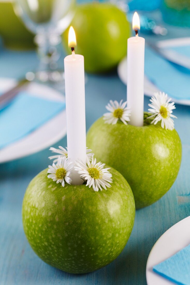 Grüne Äpfel als Kerzenhalter, dekoriert mit Kamillenblüten auf Esstisch
