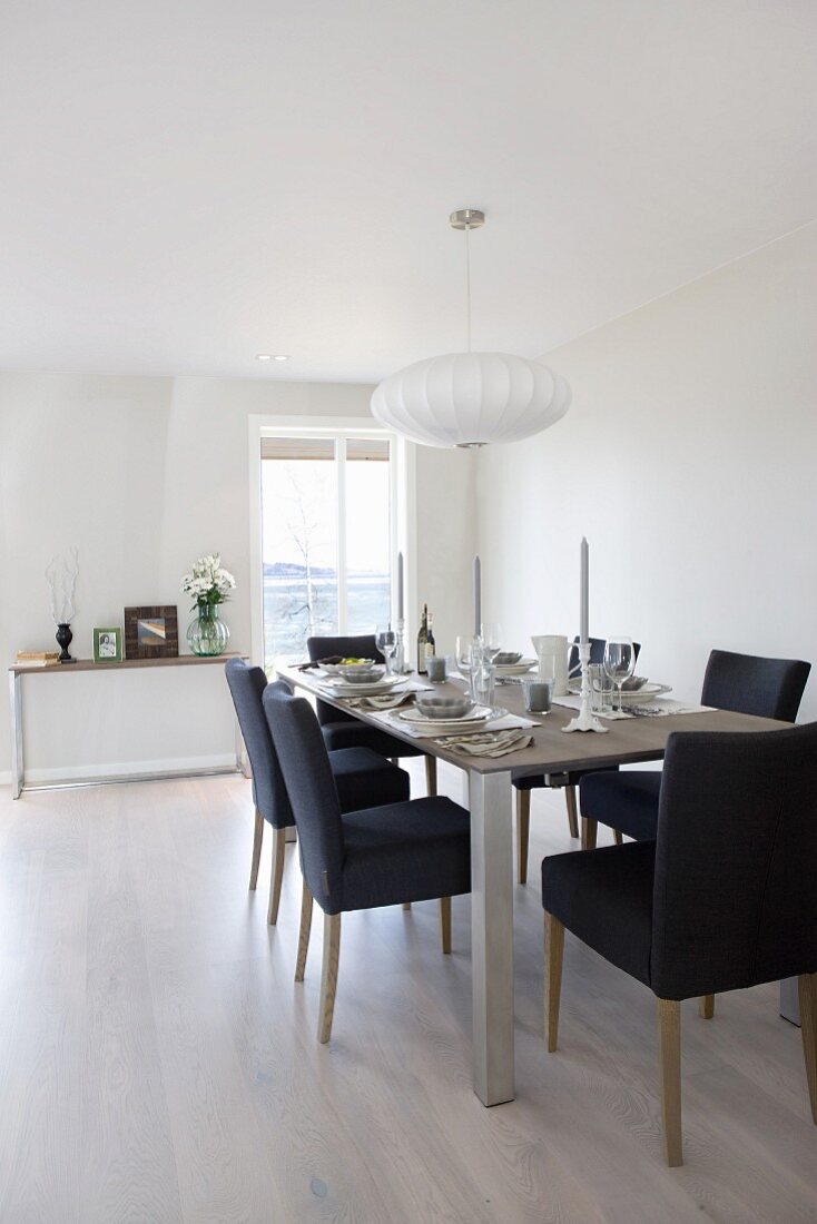 Dark blue upholstered chairs around festively set dining table in white, Scandinavian interior