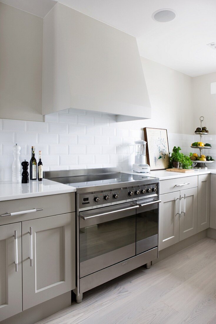 Extractor hood above electric cooker in Scandinavian cooker with pale grey fronts