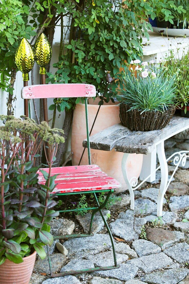 Dekostäbe für den Garten, alte Gartenmöbel und Topfpflanzen auf Steinplaster