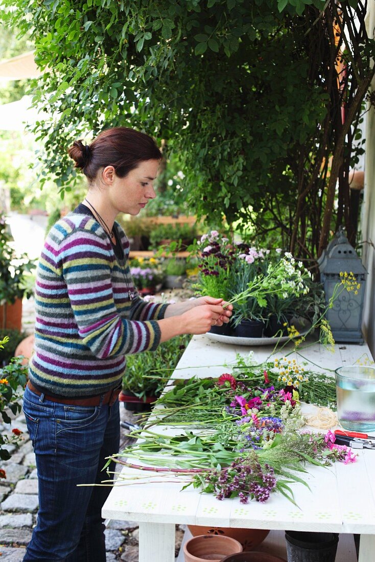 Florist tying bouquet at table in cottage garden