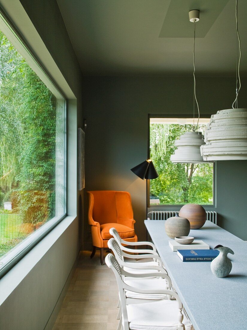 Raum mit breiter Fensterfront zum Garten & länglichem Tisch im Konferenzstil