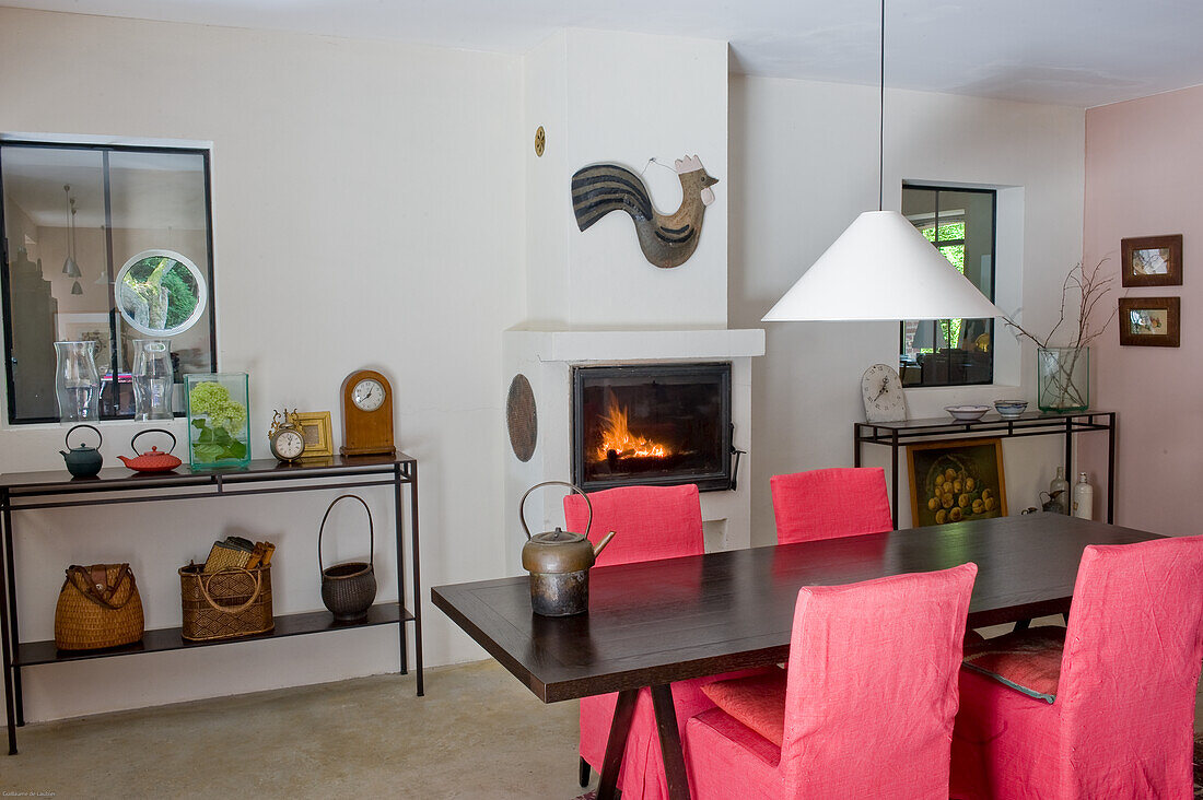 Wooden table with red chairs and fireplace in the dining room