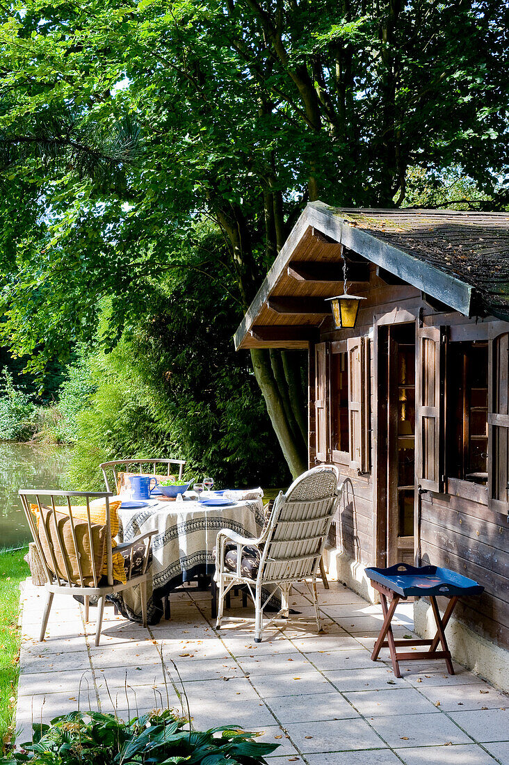 Shed with table set by the water in summer