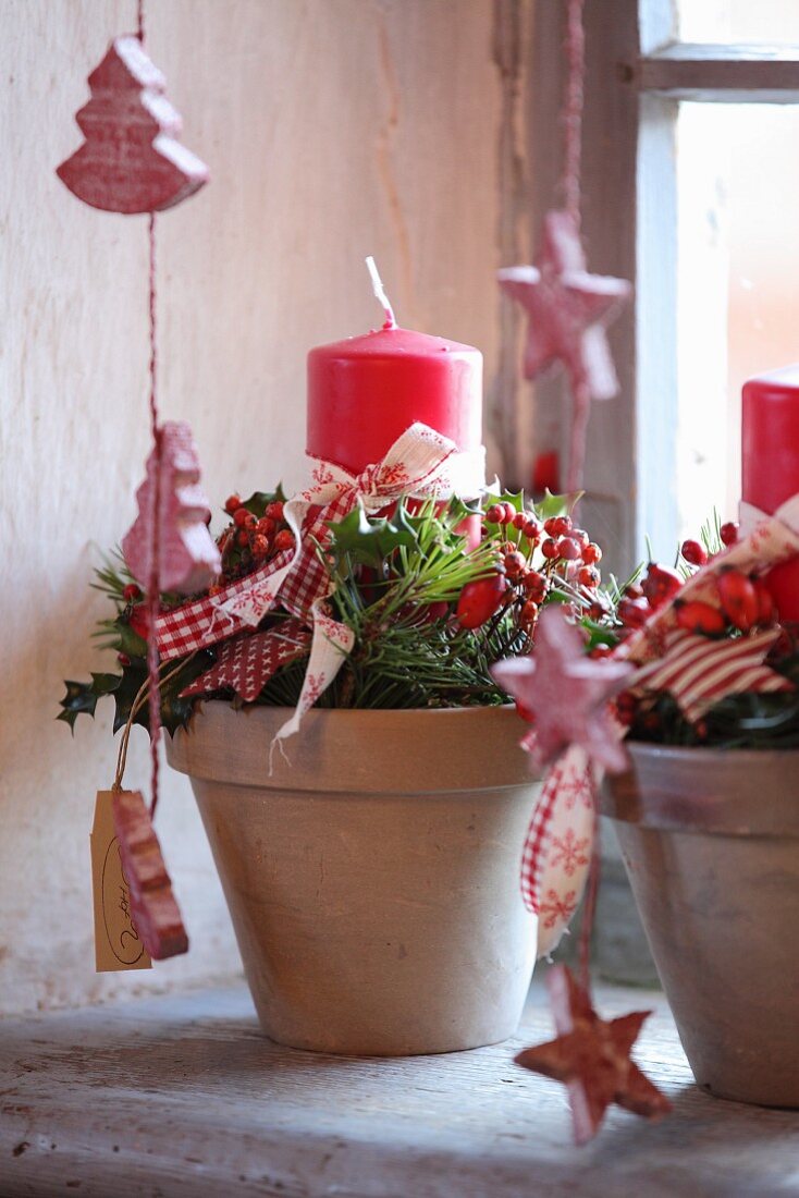 Rustikale Weihnachtsdeko mit Zweigen und Kerze im Pflanztopf