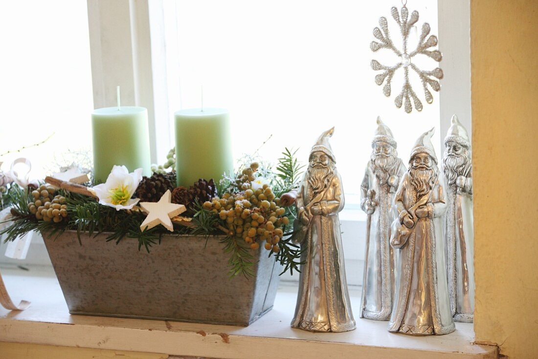 Rustic arrangement with candles next to silver Father Christmas figurines
