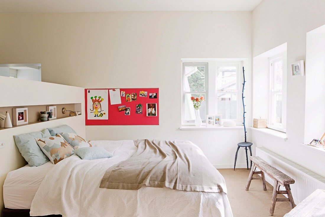 Kopfteil eines Doppelbetts als Raumteiler zur Ankleide; Magnetbord mit Kinderzeichnungen und Stuhl-Skulptur im Hintergrund