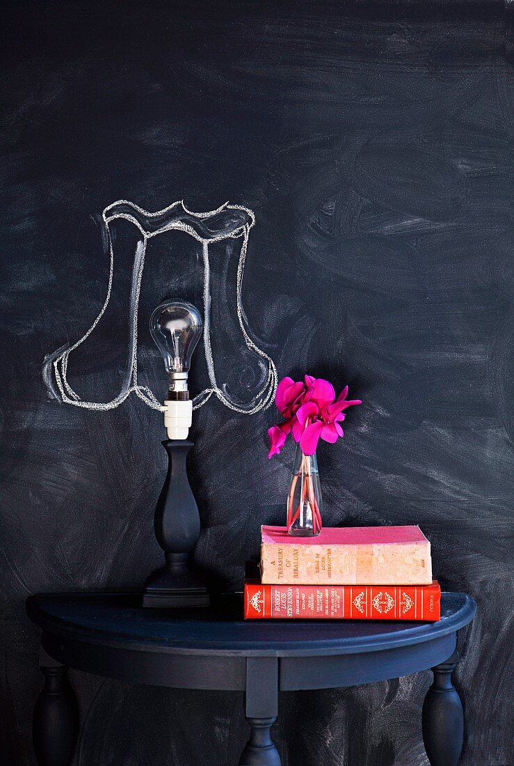 Wall painted with blackboard paint with chalk lampshade drawn around naked lamp bulb on console table