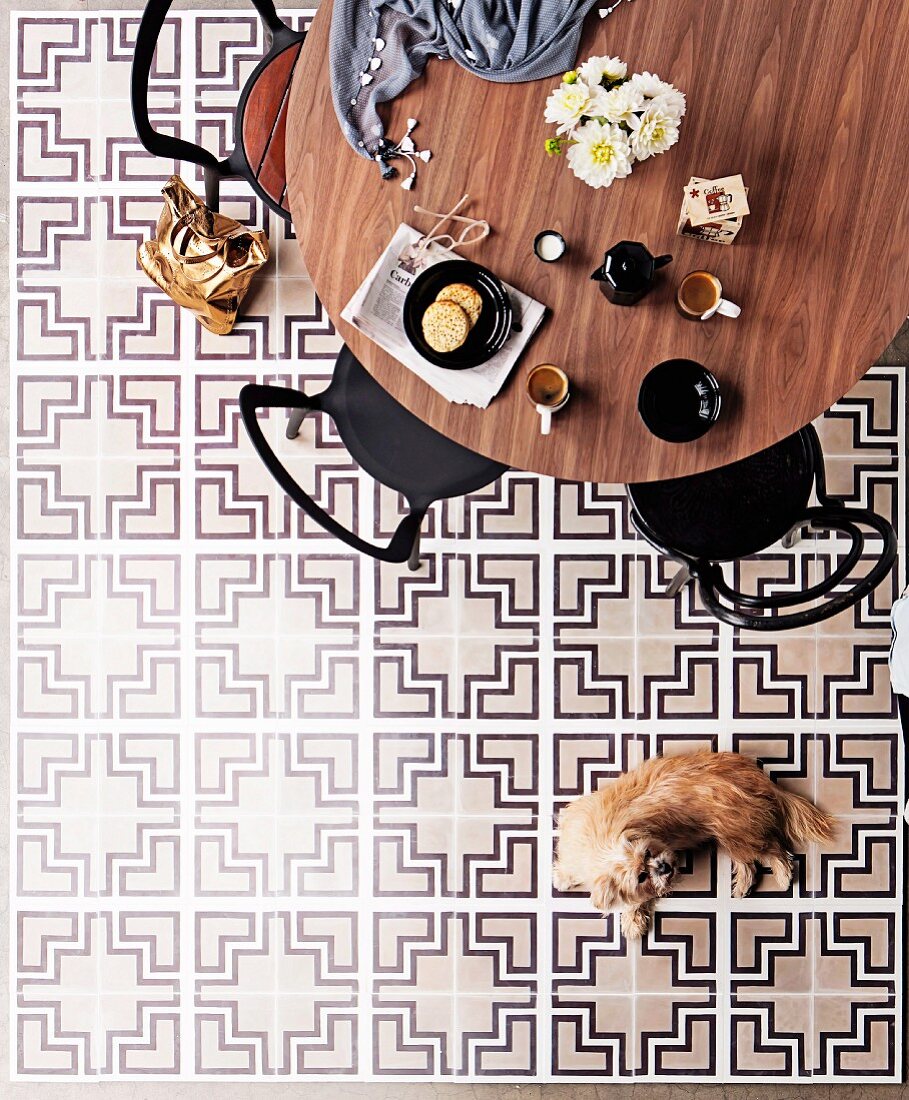 Runder Esstisch mit Stühlen auf Fliesenboden mit dekorativen grafischen Muster in Schwarz, Weiß & Grau