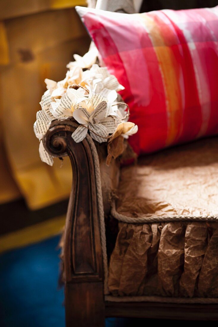 Gemustertes Kissen auf Sessel, Armlehne mit Papierblumen dekoriert