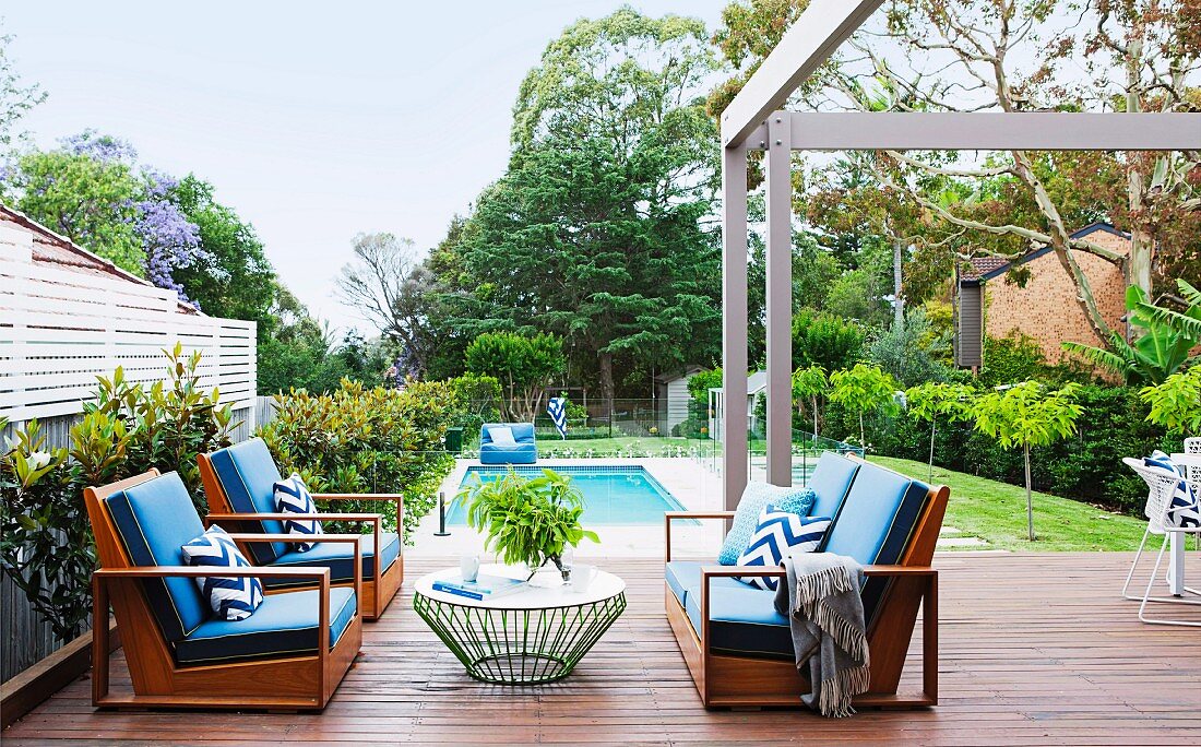 Gemütliche Outdoormöbel mit blauen Polstern auf Terrasse, im Hintergrund Pool