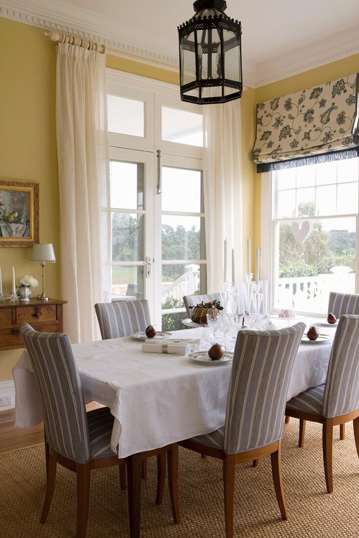 Christmas decorated dining table with upholstered chairs in the dining room with yellow tinted walls