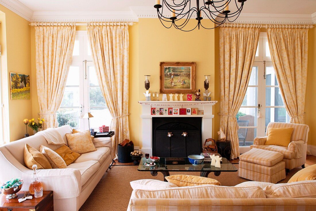 Polstergarnitur mit Couchtisch und Kamin im Wohnzimmer mit französischen Fenstern und gelb getönten Wänden