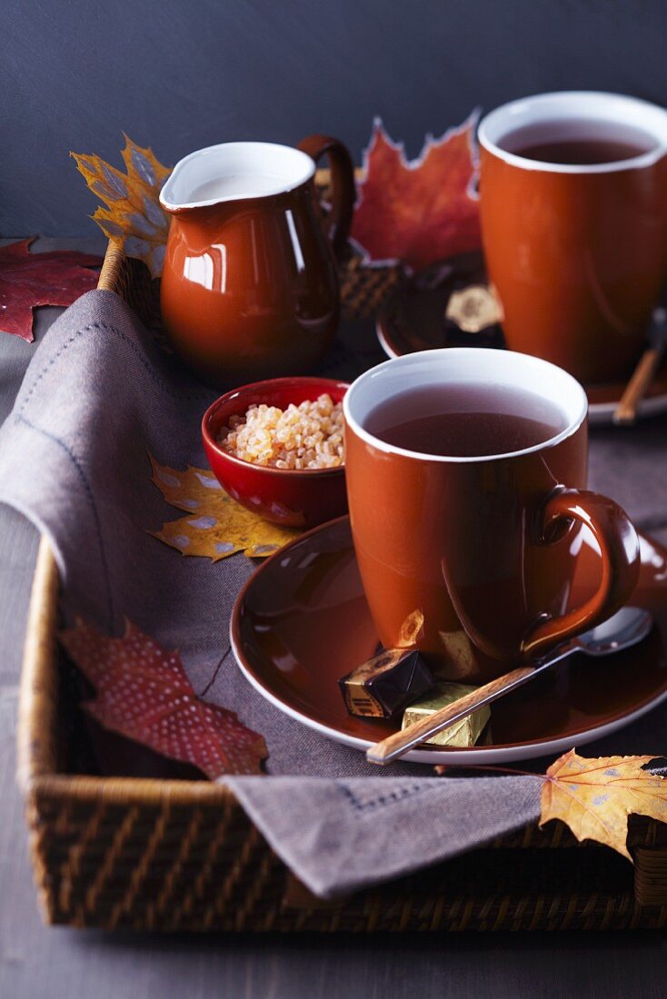 Tablett mit Teetassen, Zucker und Milch, dekoriert mit Herbstblättern