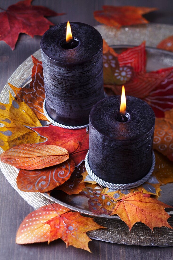 Tablett mit Kerzen und bemalten Herbstblättern