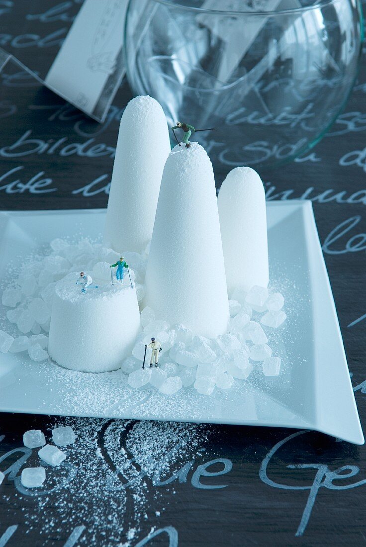 Zuckerhut mit kleinen Figuren auf weißem Teller