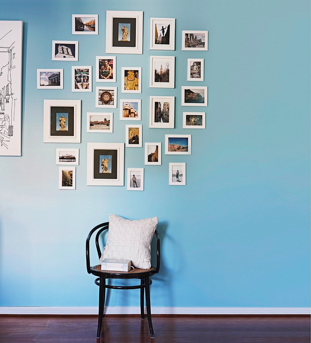 Thonetstuhl mit weißem Kissen unter gerahmter Bildersammlung an blauer Wand