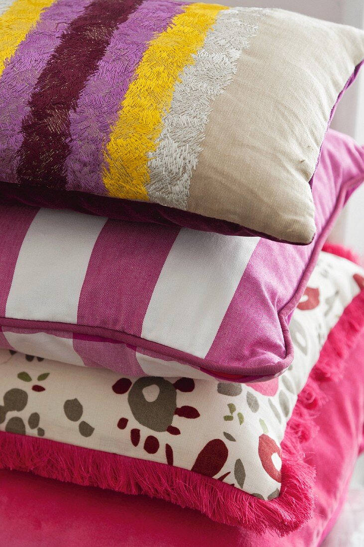 Stack of decorative pillows in assorted pink and purple fabrics