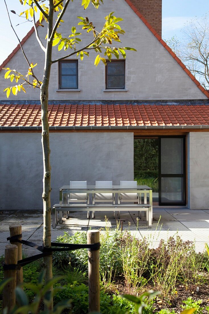 Terrassenplatz vor Anbau eines Wohnhauses an grau verputzter Giebelfassade