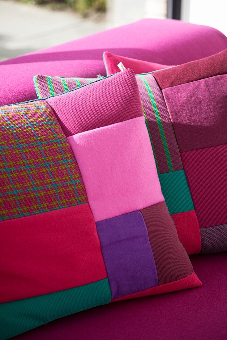 Patchwork scatter cushions in various shades of red and pink on deep pink couch