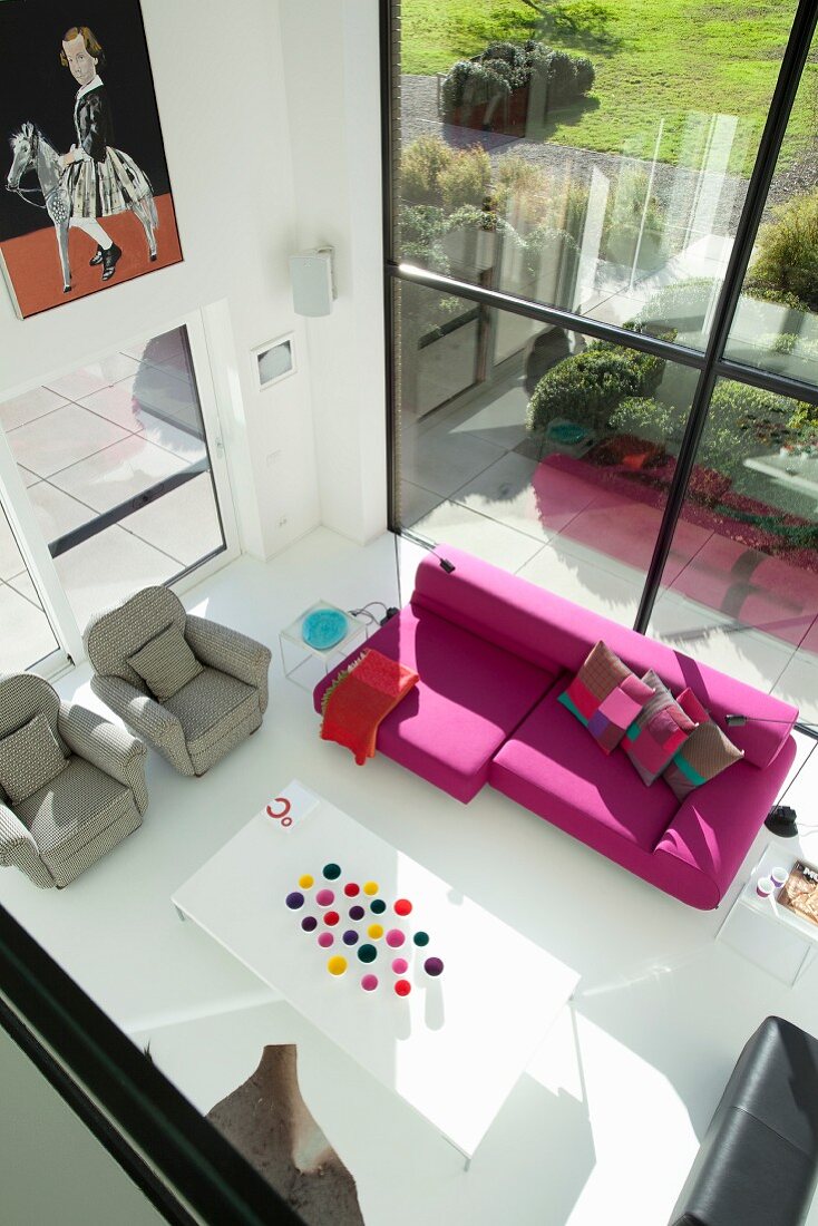 Blick von der Galerie auf den Loungebereich mit Gartenblick durch Panoramafenster