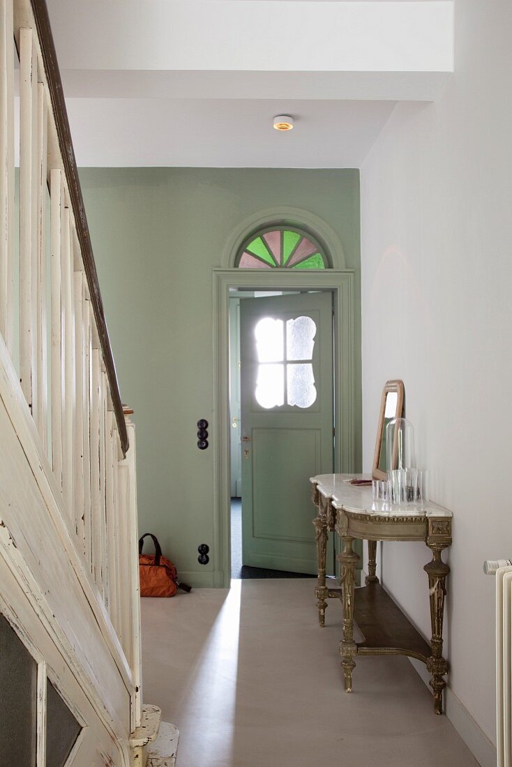 Stylishly restored hallway with wooden staircase and vestibule door with nostalgic glass panel and stained glass transom window