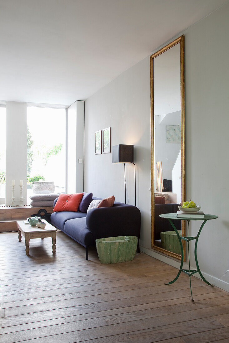 Minimalist living room with dark blue sofa, side tables and high wall mirror