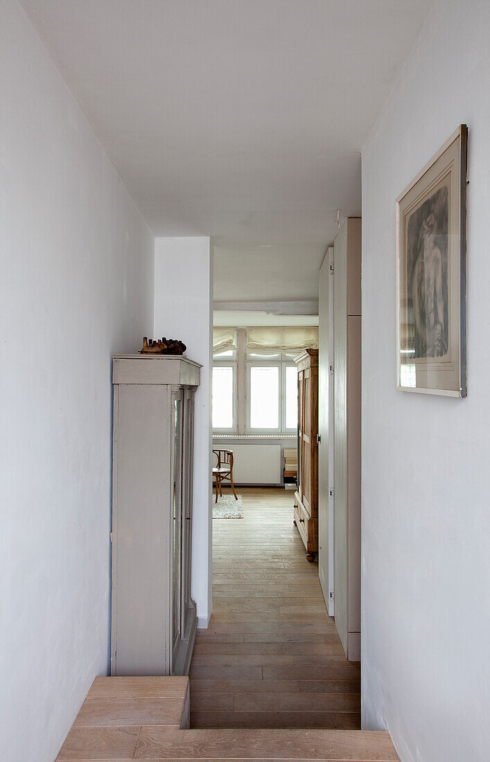 Long hallway with wooden floor and picture on white wall