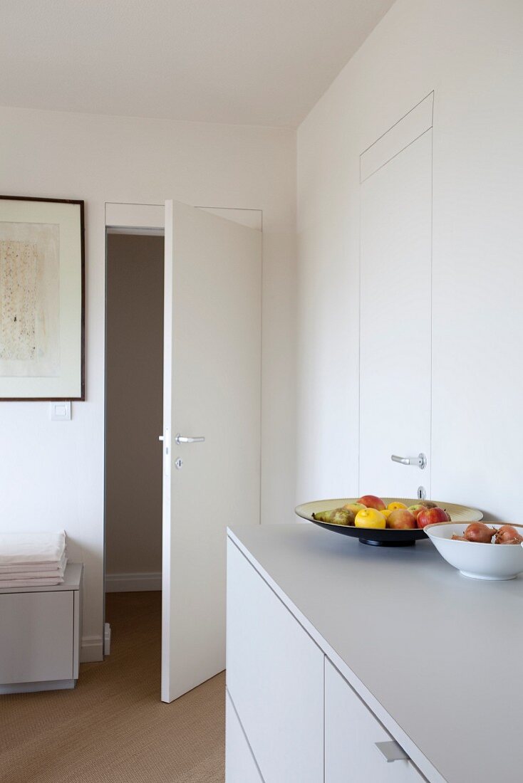 Fruit bowl on white sideboard and open interior door