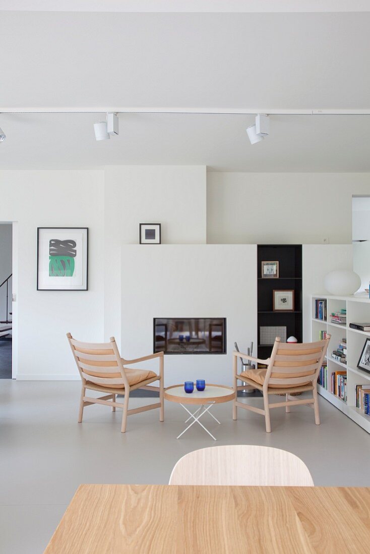 Wohnzimmer mit schlichten Designermöbeln im skandinavischen Stil und weißen Einbauten