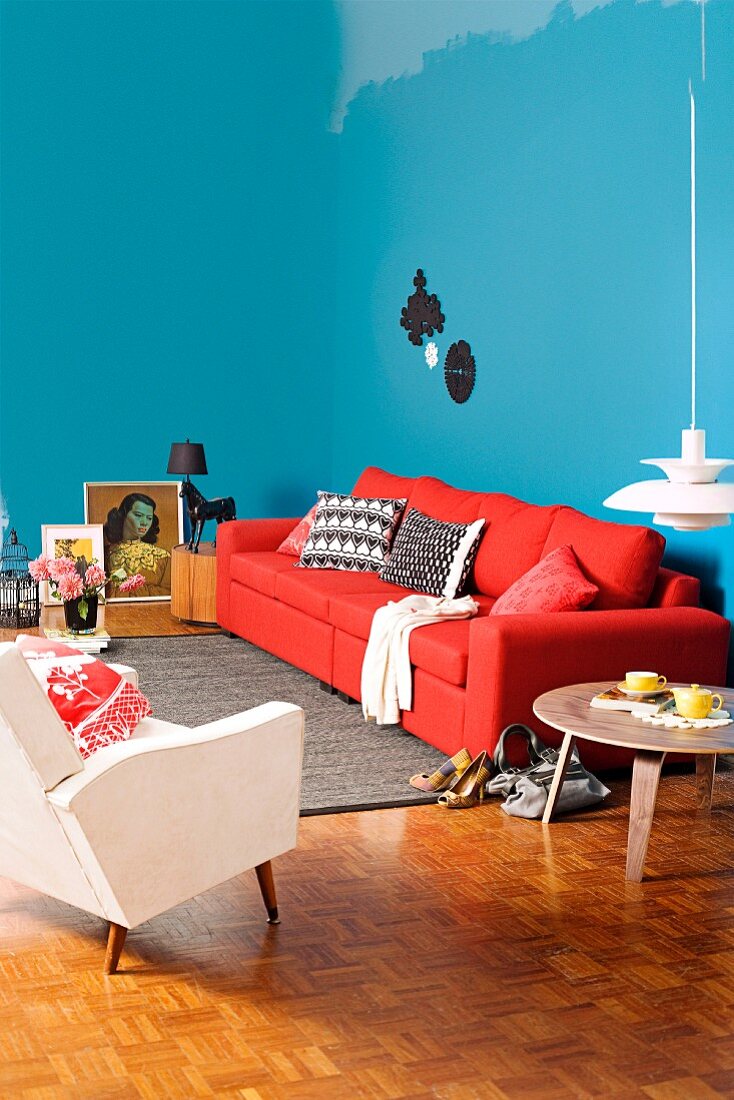 Living room with a feminine touch, blue walls and red sofa