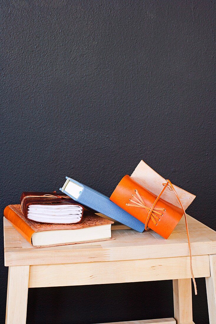 Books on a wooden stool in front of a black wall