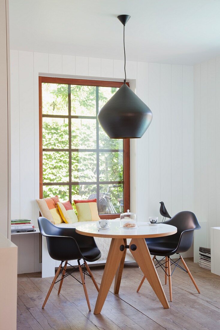 Runder Klassiker Tisch und schwarze Schalenstühle mit Holzgestell unter Designer Hängeleuchte mit schwarzem Metallschirm in ländlichem Esszimmer
