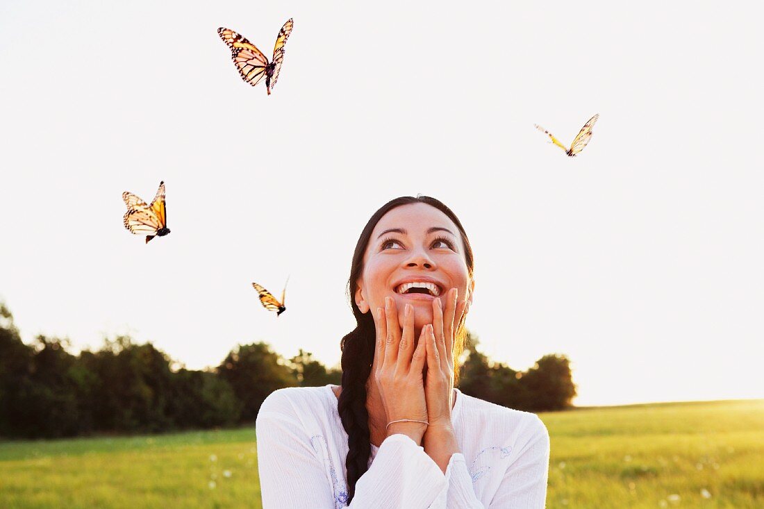 Frau mit herumfliegenden Schmetterlingen auf einer Wiese