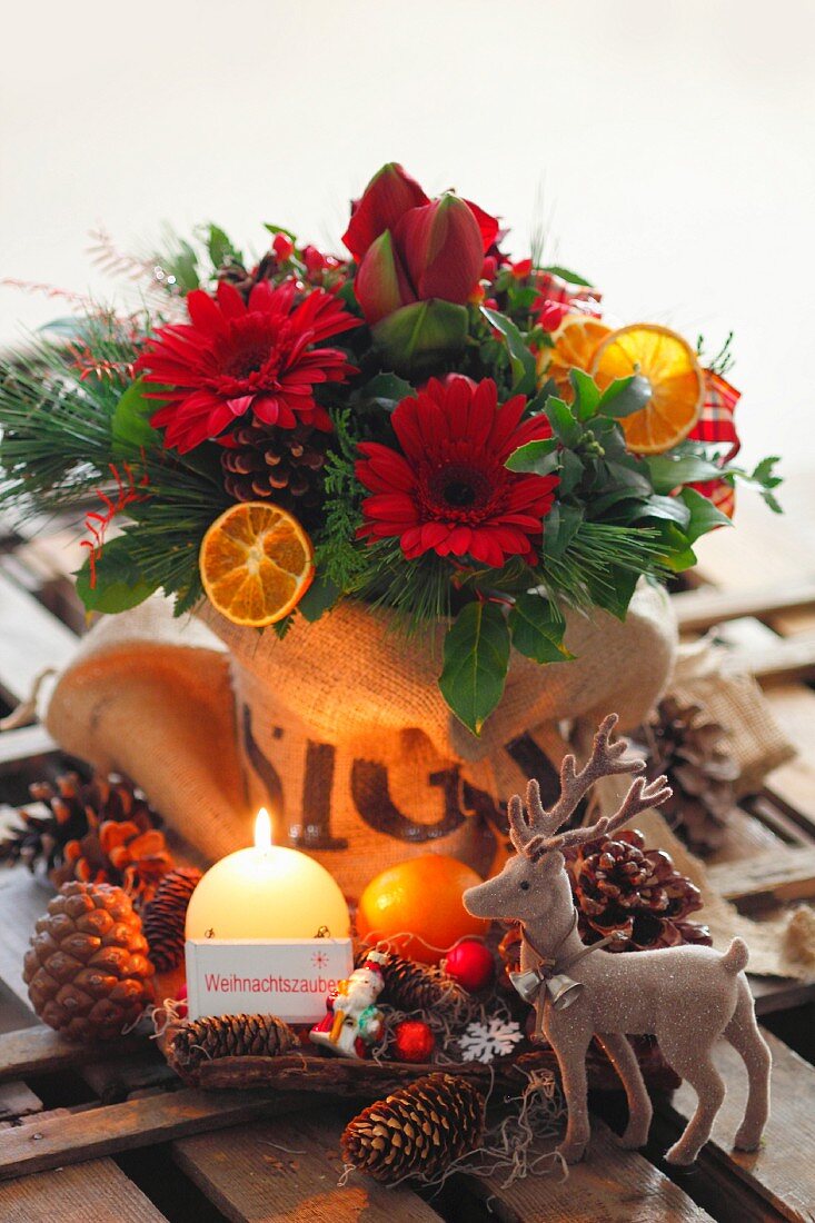 Weihnachtlicher Blumenstrauss, Hirschfigur, Pinienzapfen und Kerzen