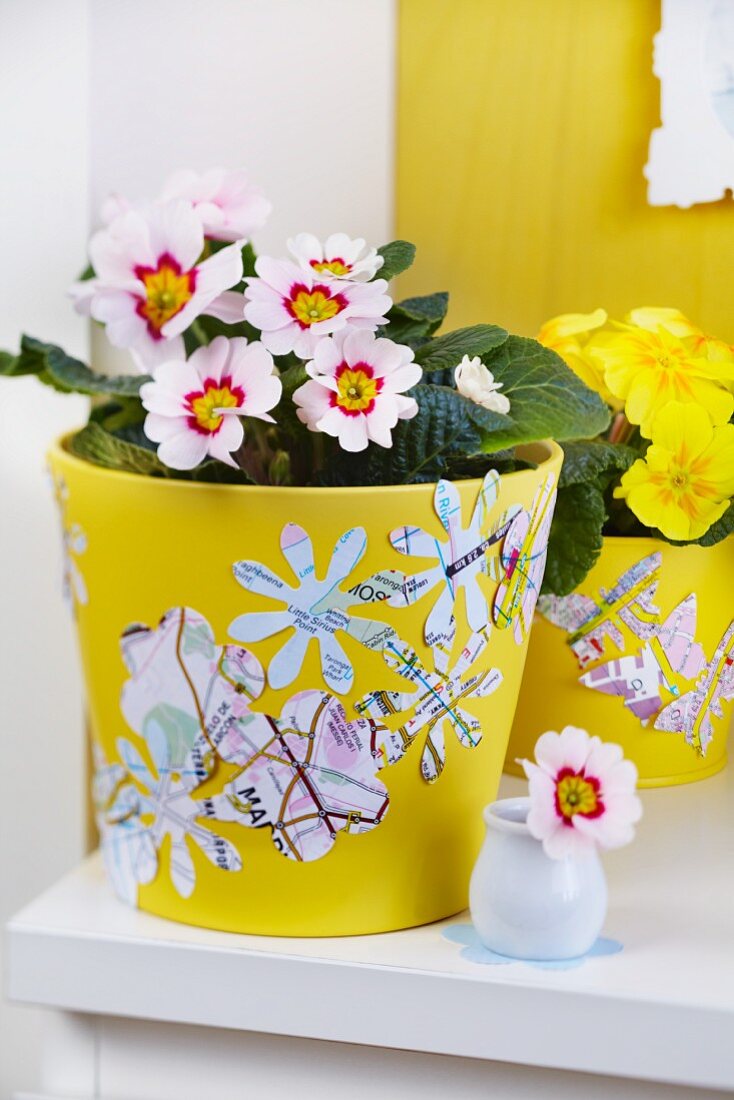 Flower and butterfly shapes punched out of maps decorating yellow flowerpots